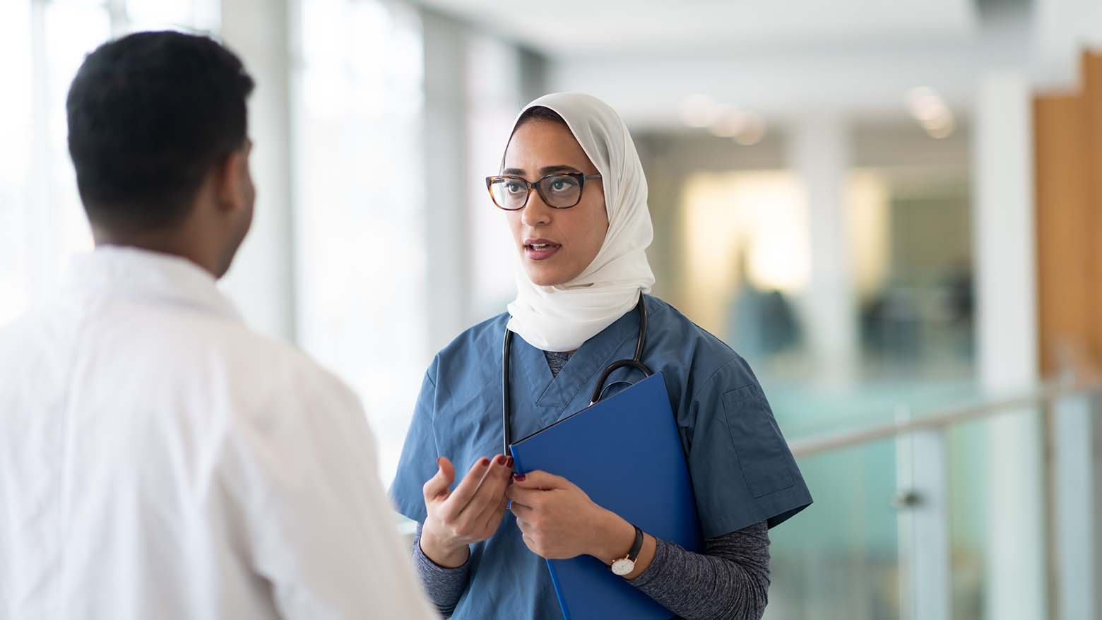 A female resident speaks to another doctor in a hospital