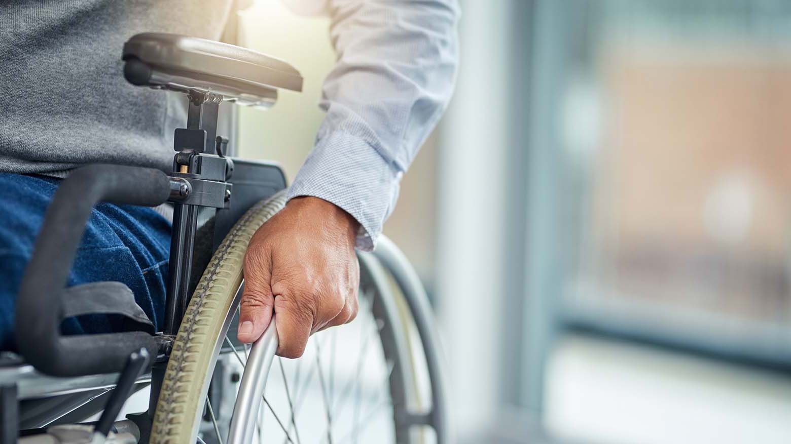 Close up of a man's hand on the wheel of the wheelchair he's sitting in