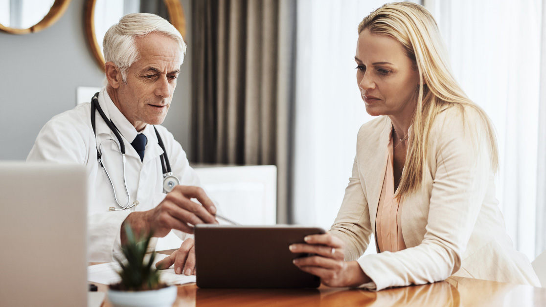 A doctor shows information on a tablet to a patient