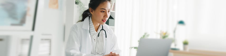 A doctor looks at her laptop screen