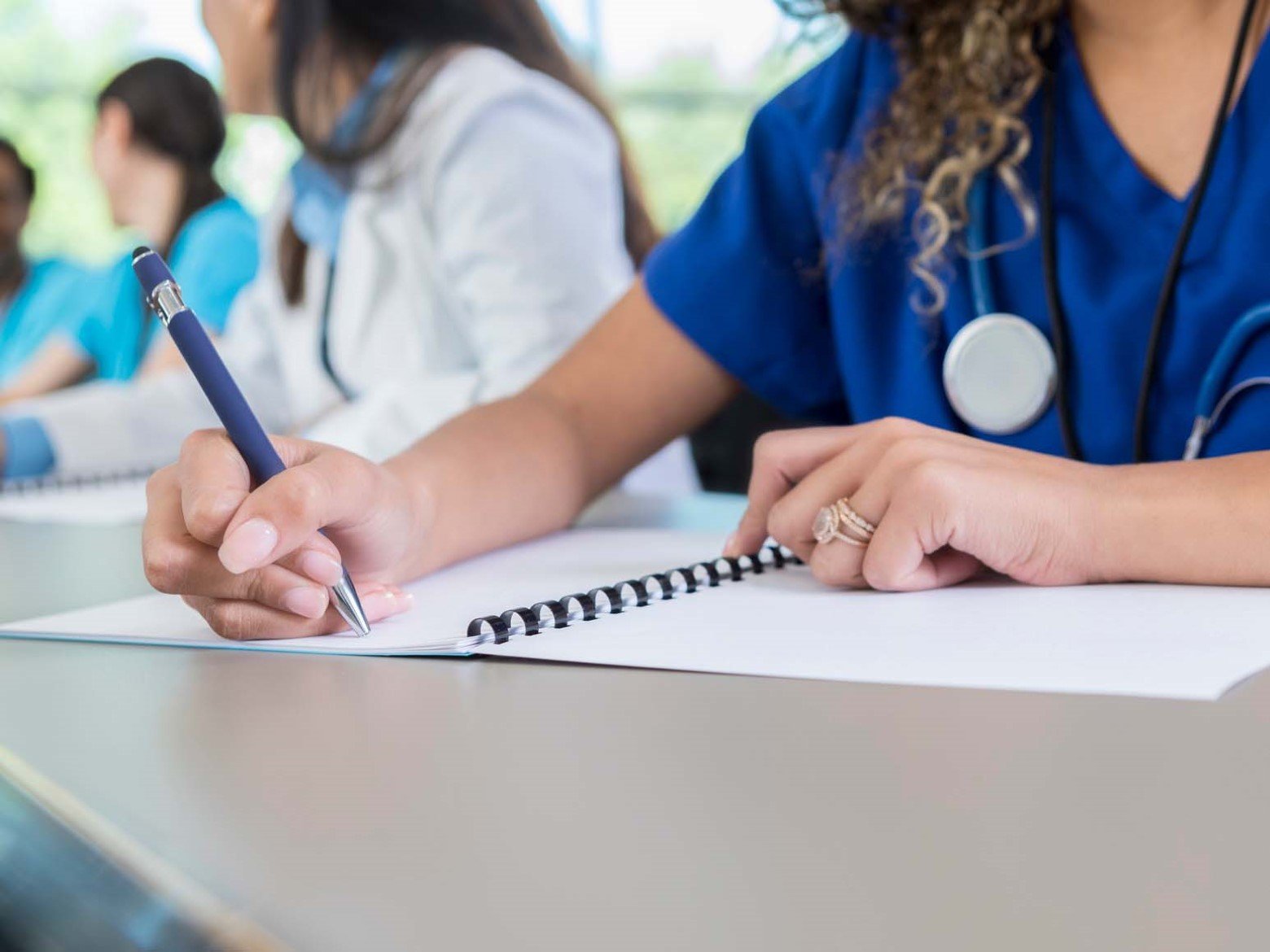 A medical student sits in class while writing in a notebook