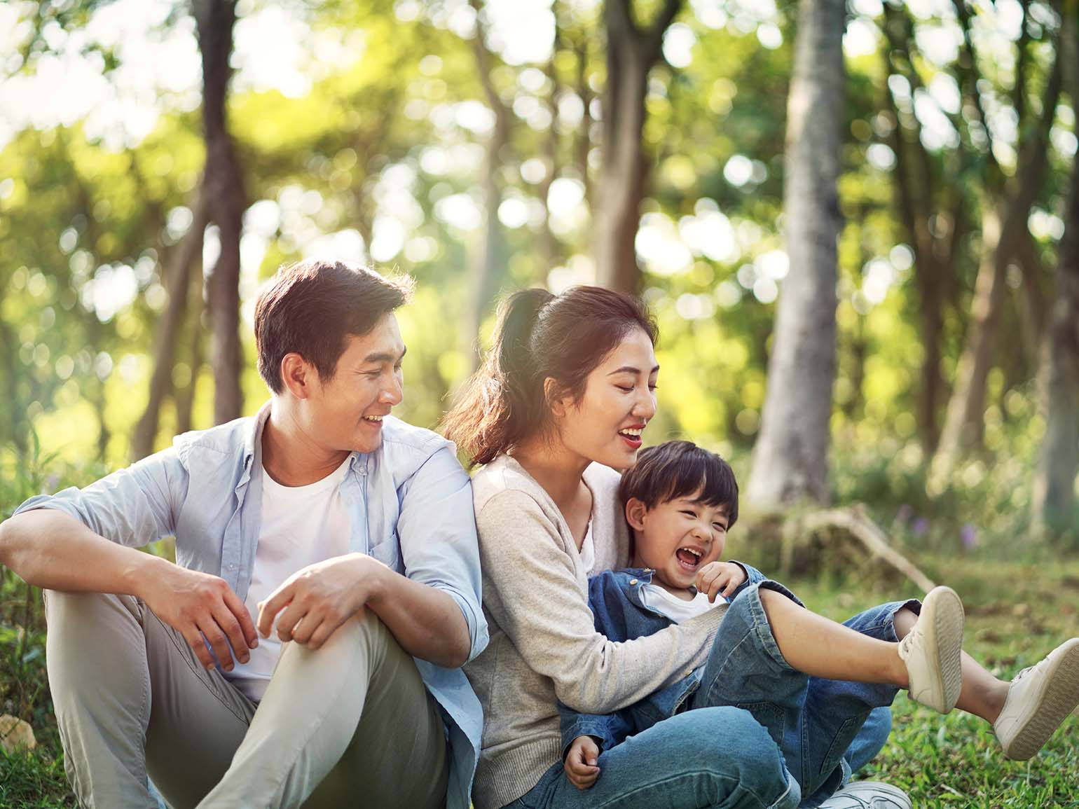 A mother and father playing with their kid in a park.