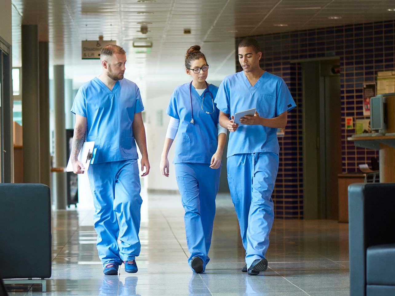 A group of medical residents discuss while walking through a hospital hallway