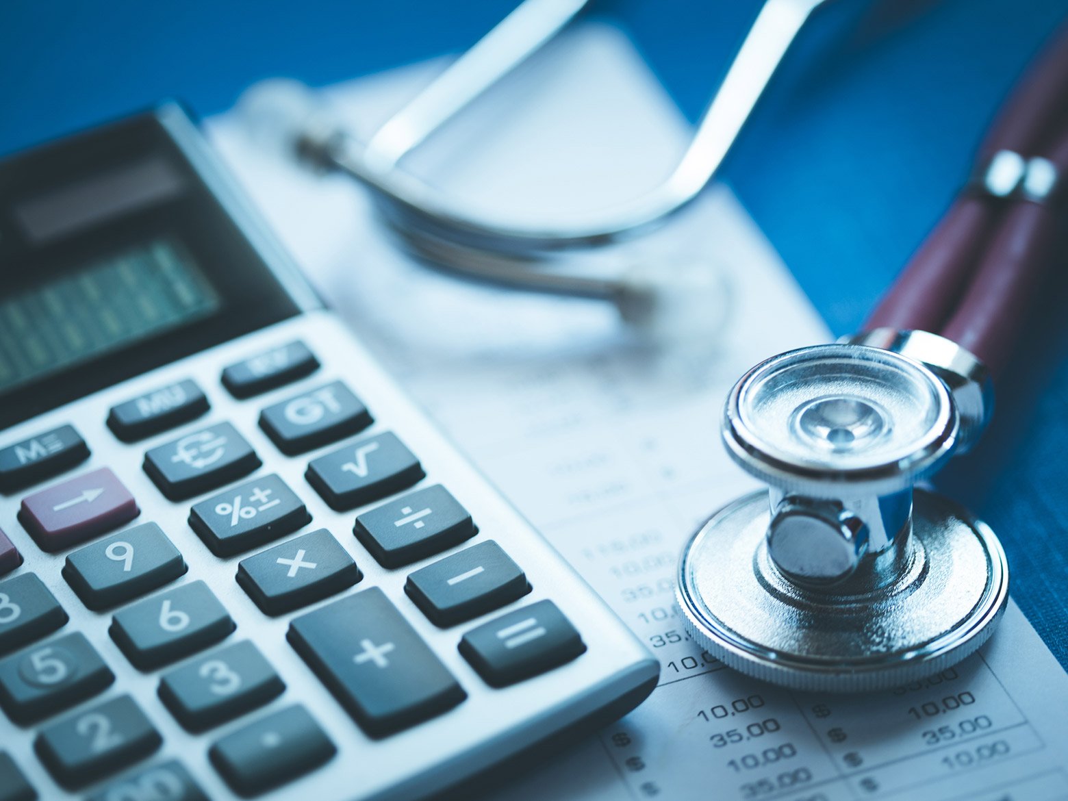 A stethoscope and calculator on top of a printed spreadsheet