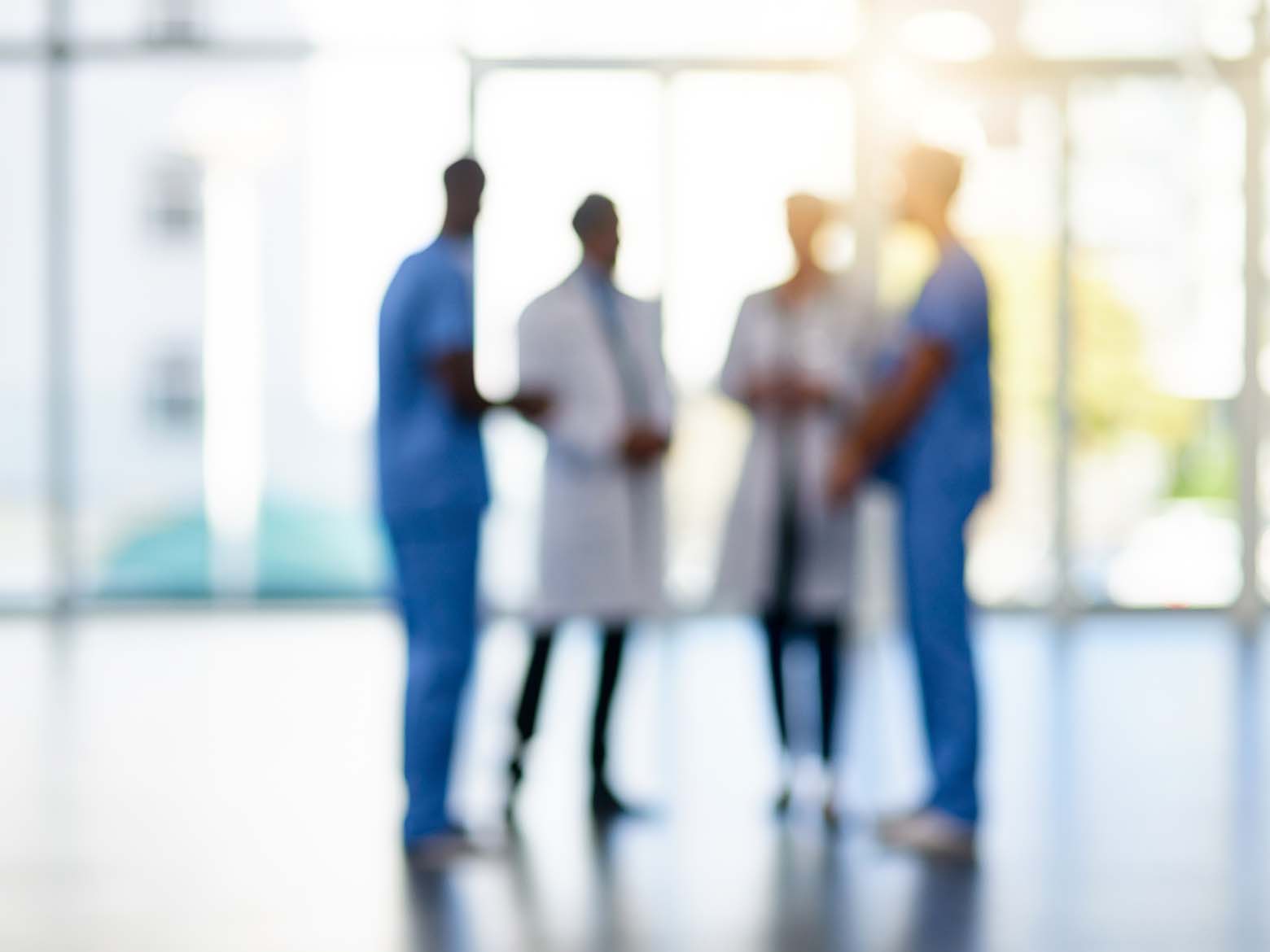 A group of doctors have a conversation in the distance at a hospital