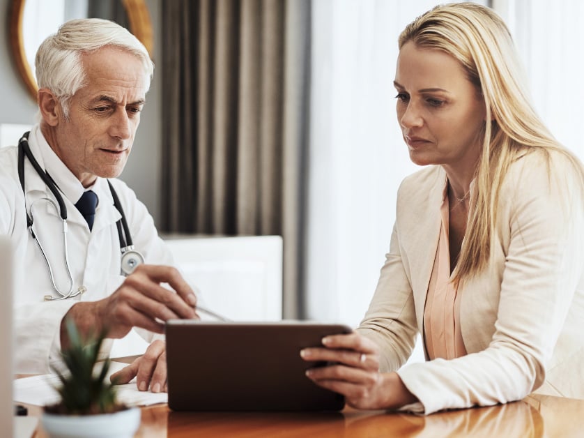 A doctor shows information on a tablet to a patient