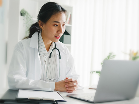 A doctor looks at her laptop screen