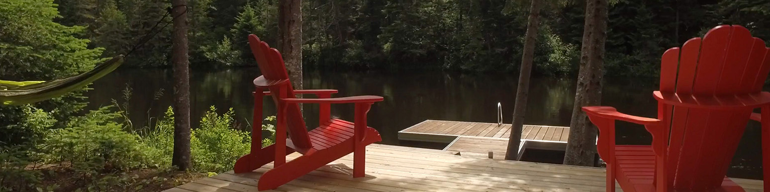 Two muskoka chairs on a dock by a lake